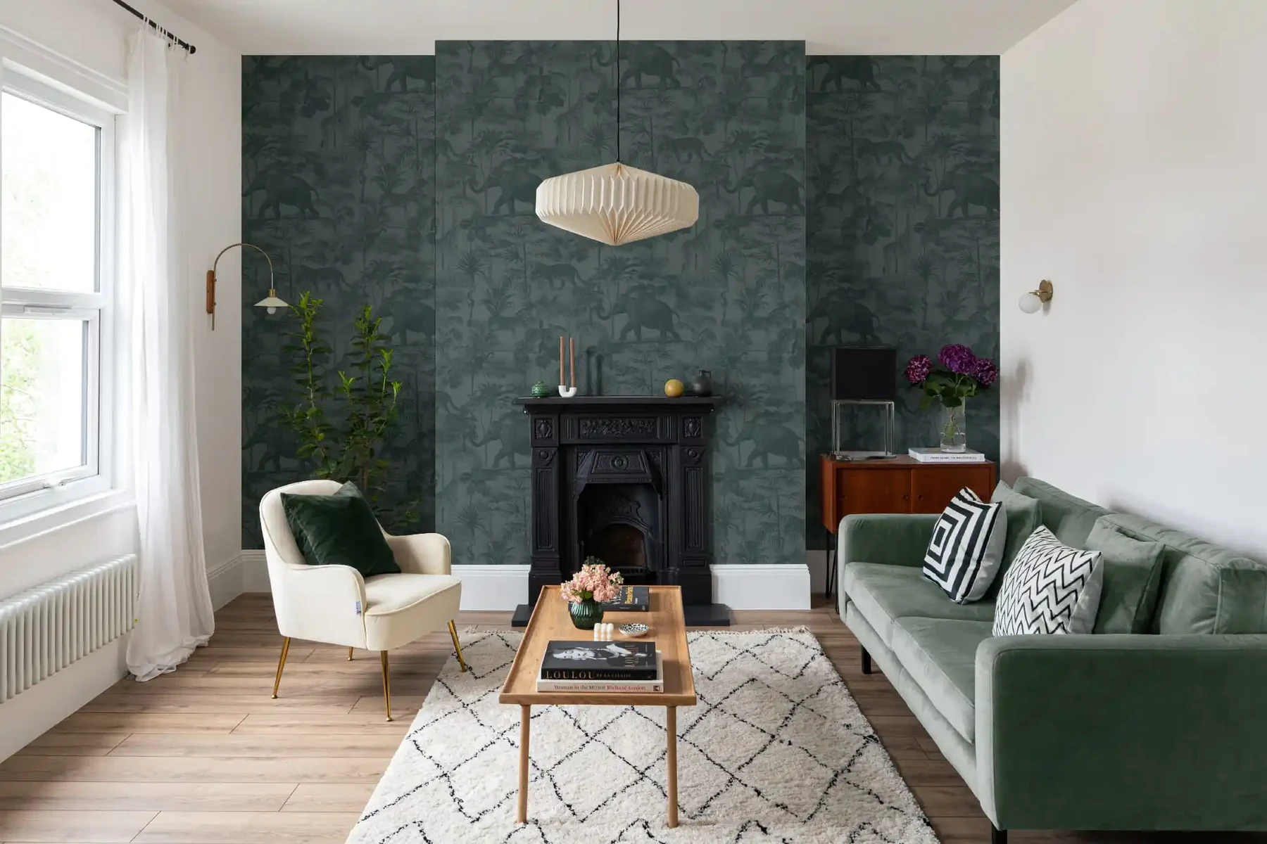 A deep green patterned wall behind a fireplace in a furnished living room